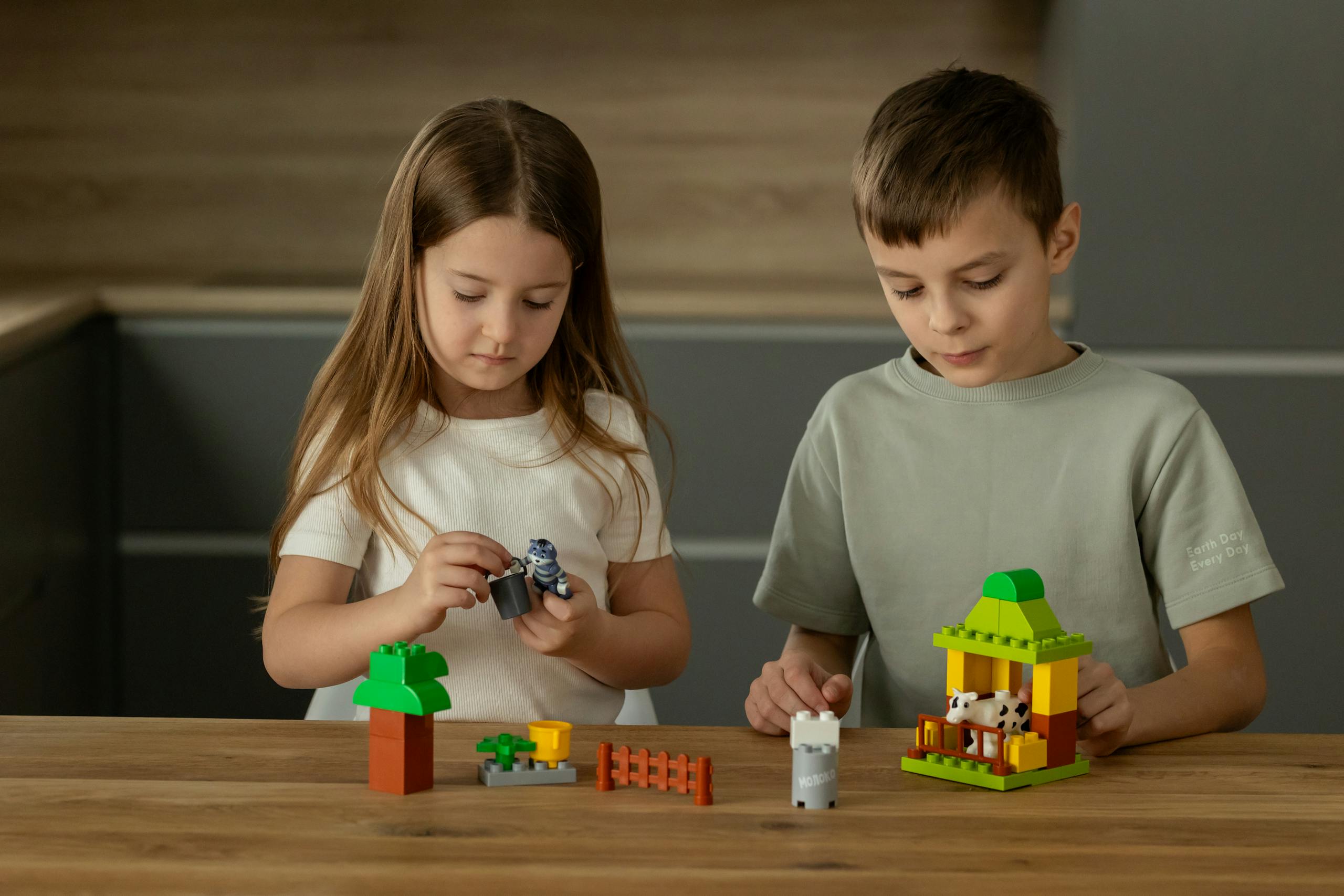 Two young children playing and assembling toys on a wooden table, fostering creativity.